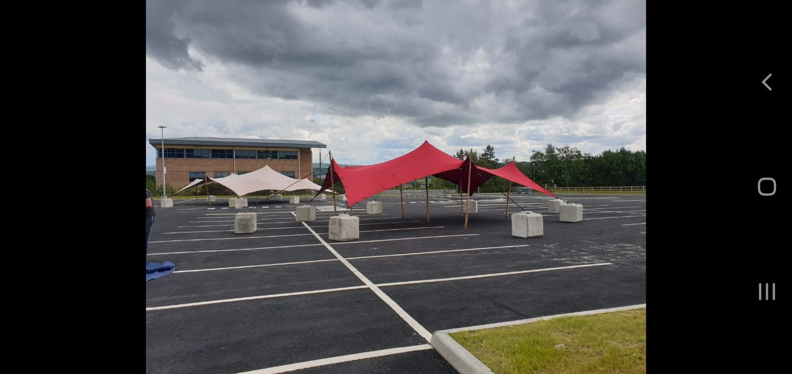 Red and cream stretch tents set up in a large car park under dramatic cloudy skies