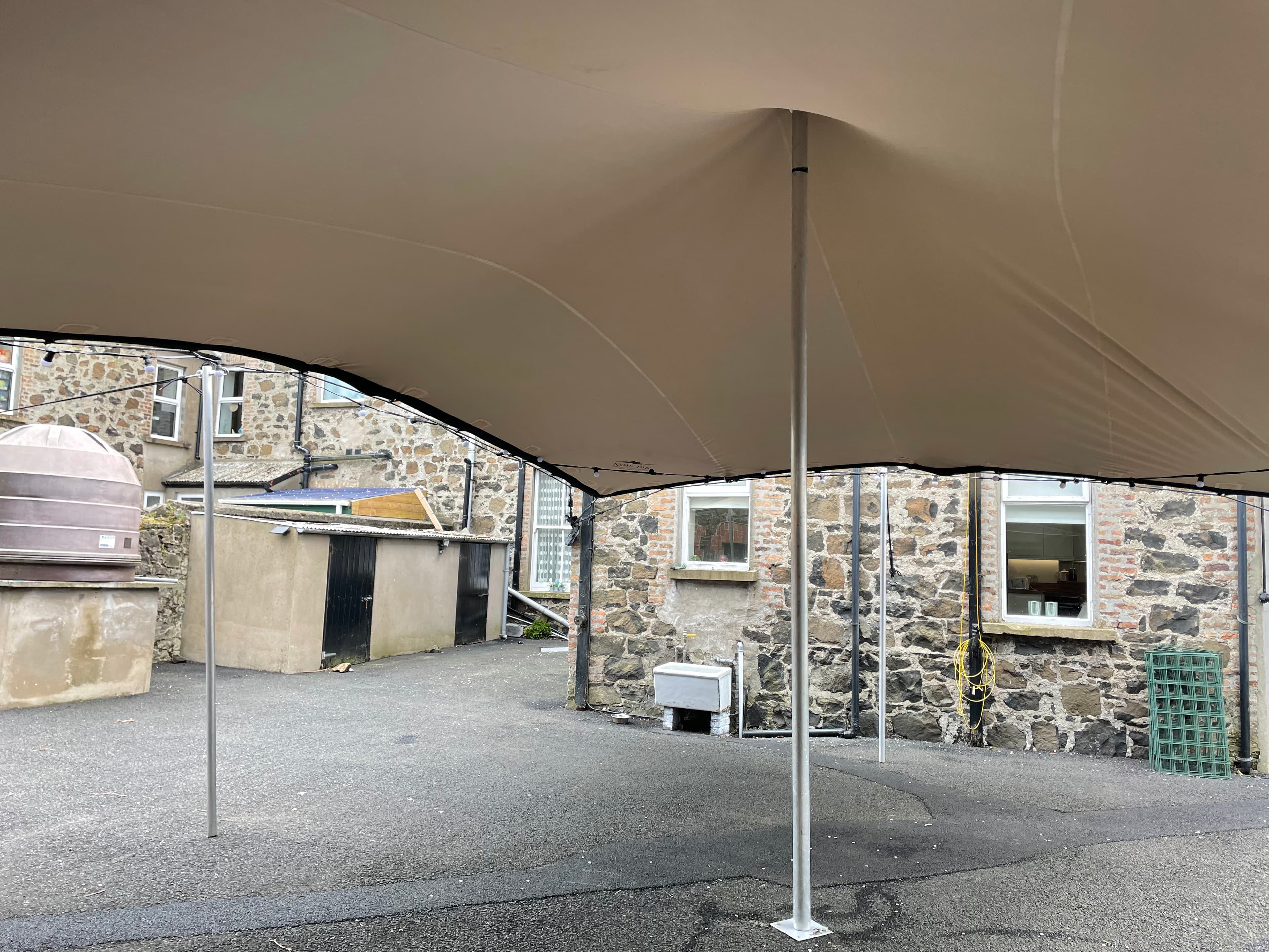 Interior view of a stretch tent installed over a paved courtyard beside stone buildings