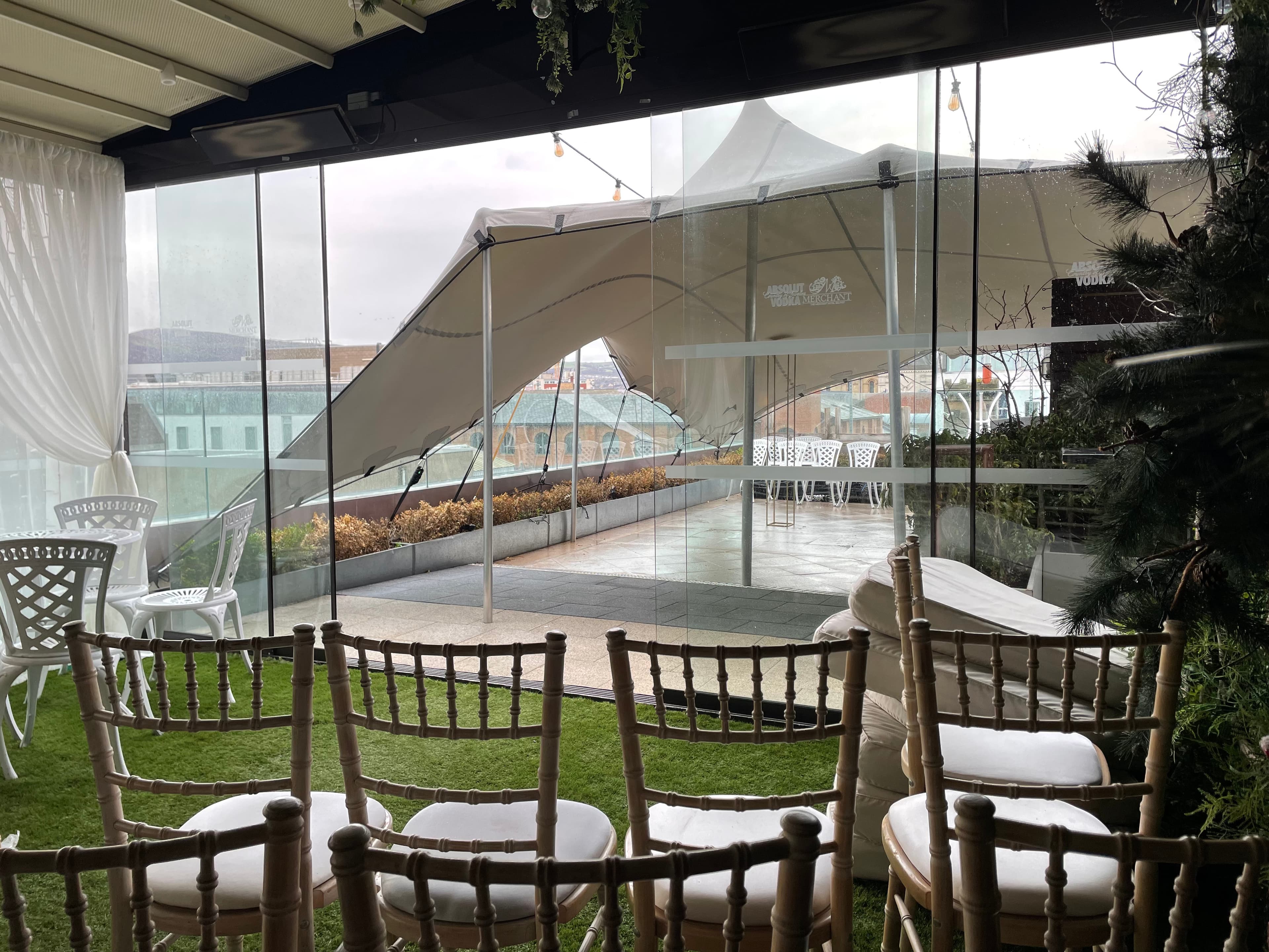 Indoor seating area looking out through glass onto a rooftop stretch tent set up on a terrace