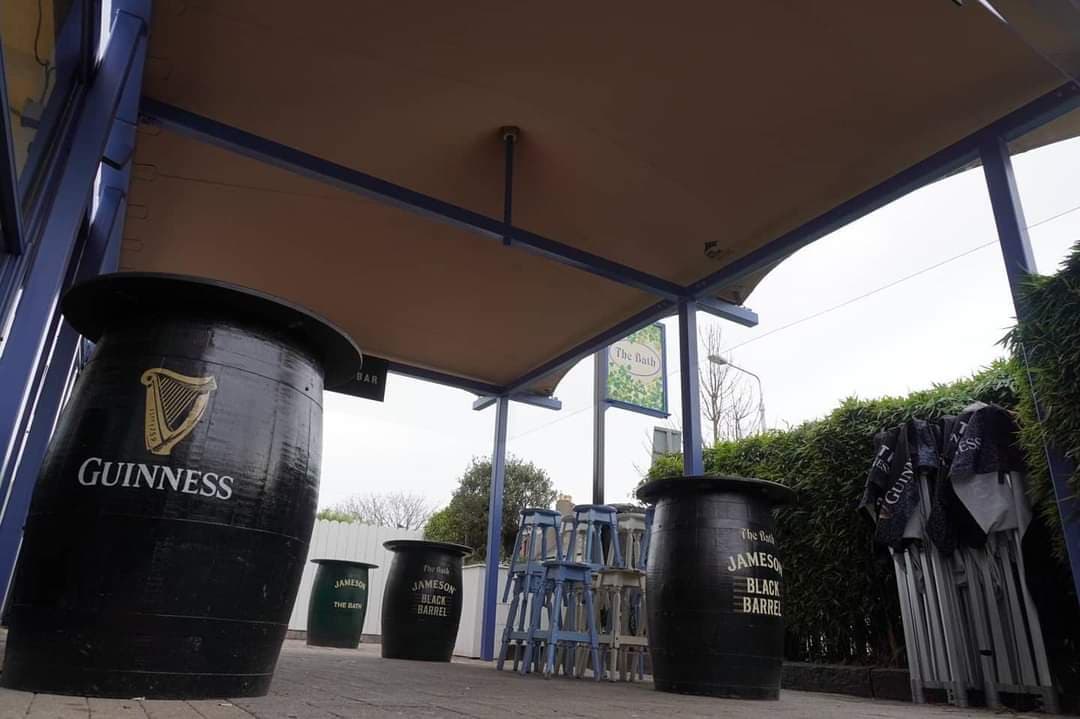 Covered pub terrace with stretch-tent canopy and branded barrel tables